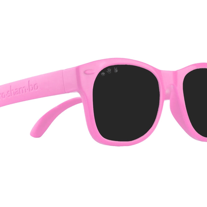 Roshambo Baby glitter pink sun glasses with black lens against white backdrop