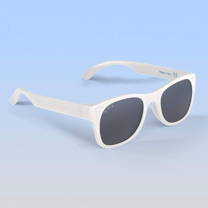 Roshambo Baby white sun glasses with grey lens agains blue backdrop